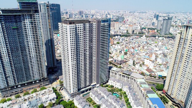 Un edificio de gran altura con diseño arquitectónico moderno, rodeado de otros edificios altos y una zona urbana densamente poblada.