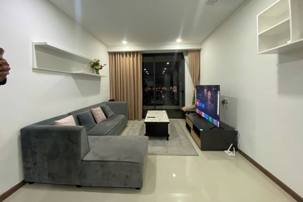 A modern living room with a grey sectional sofa, a coffee table, and a flat-screen TV.