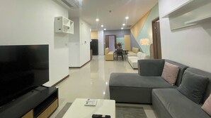 Una sala moderna con televisión de pantalla plana, un sofá, una mesa de centro y un comedor al fondo.