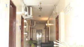 Corredor com ventoinha no teto, aparelhos de ar condicionado e uma poltrona de couro preta.