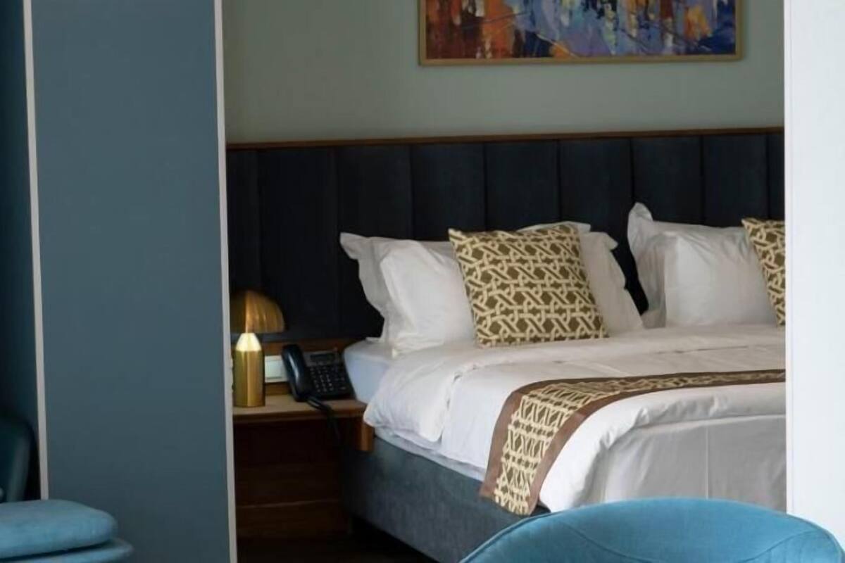 Ein Hotelzimmer mit Bett, Nachttisch, Lampe und Stuhl.