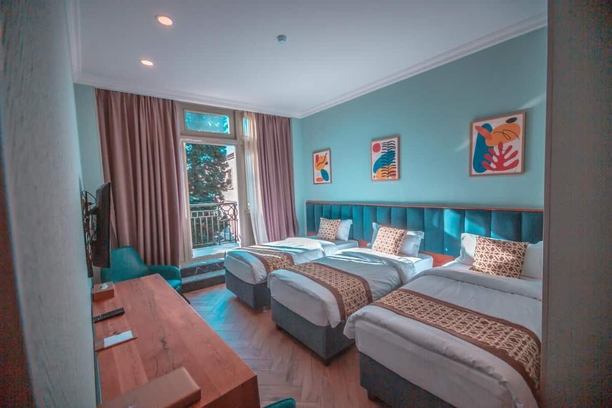 Ein Hotelzimmer mit zwei Betten, einem Holztisch, einem Fernseher und Bildern an den Wänden.