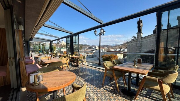Un'area salotto all'aperto con tavoli e sedie, un pavimento decorato e vista sulla città.