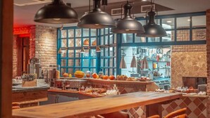 Interno di un ristorante con parete in mattoni, infissi blu e lampade a sospensione.