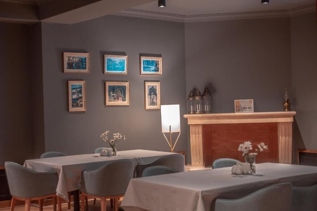 A dining area with tables and chairs, a fireplace, and framed pictures on the wall.