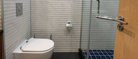 Une salle de bain moderne avec des toilettes, une douche à parois de verre et un carrelage au sol.