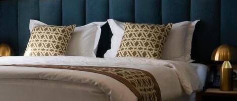 A bed with a blue headboard, white bedding, and patterned pillows.