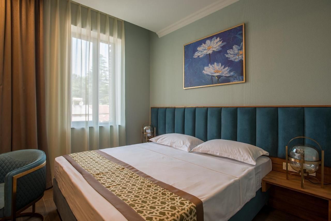 Una habitación de hotel con una cama, una silla, una mesita de noche y un cuadro en la pared.