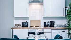 A compact kitchen with white cabinets, a wooden countertop, a stove, a sink, and a dishwasher. - Host Stay The Georgian Quarters at Bedford II and III (Liverpool)