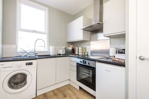 A modern kitchen with a washing machine, oven, and a window providing natural light.