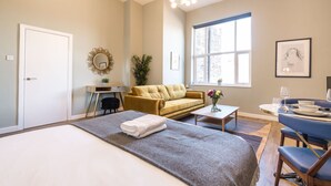 A hotel room with a bed, a sofa, a dining table with chairs, a window, and a mirror. - Host Stay The Georgian Quarters at Bedford II and III (Liverpool)