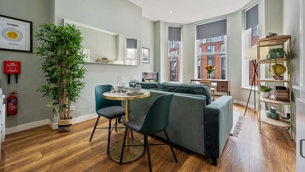 A modern living room with a green sofa, a round wooden table, and a potted plant. - Host Stay The Georgian Quarters at Bedford II and III (Liverpool)