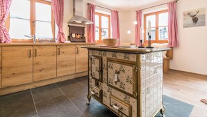 A kitchen with wooden cabinets, a tiled backsplash, and a central island with drawers. - Vacation apartment Rehkitz (Reit im Winkl)