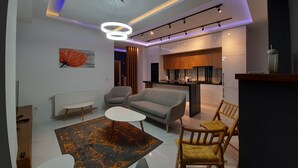 A modern living room with a sofa, chairs, a coffee table, and a kitchen area with a dining table and chairs. - Bagebi two bedroom beautiful view  (Tbilisi)