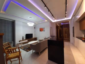 Relax in this stylish living room with a flat-screen TV, comfortable sofa, and dining area.
