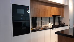 A modern kitchen with white cabinetry, a Bosch oven, and a wooden countertop. - Bagebi two bedroom beautiful view  (Tbilisi)