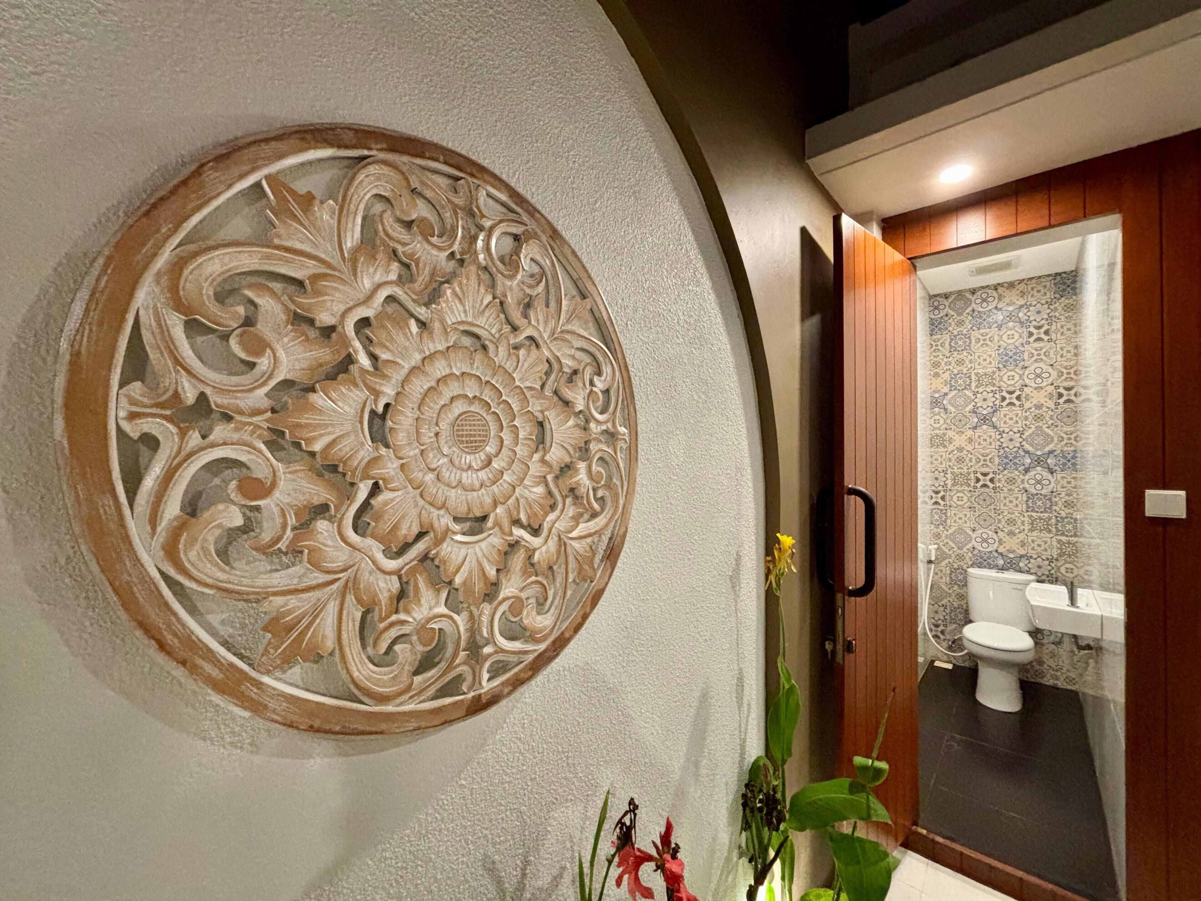 A bathroom with a decorative wall panel, a toilet, and a sink.