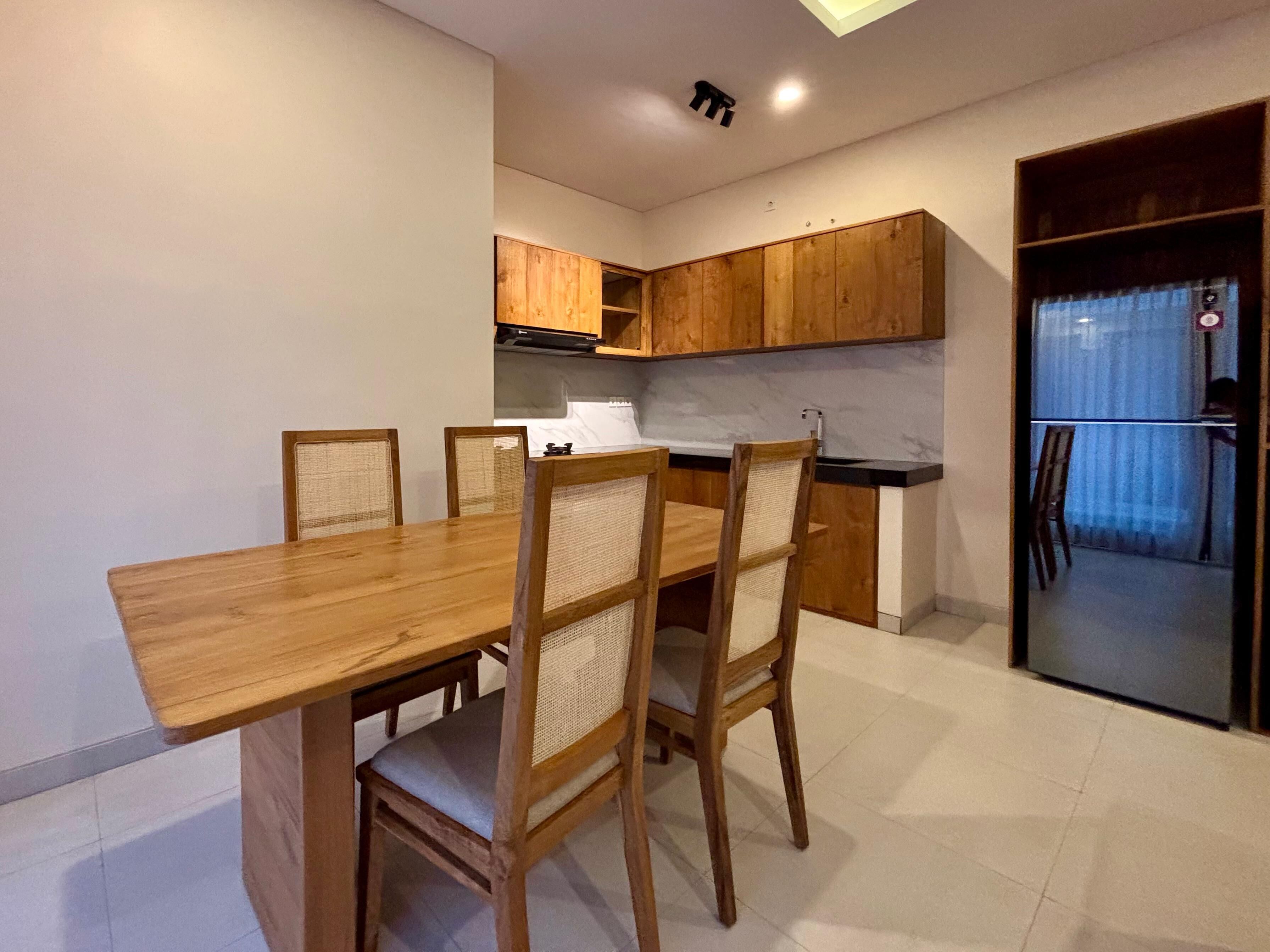 A dining area with a wooden table and chairs, a kitchen with wooden cabinets, and a sliding glass door leading to a balcony.