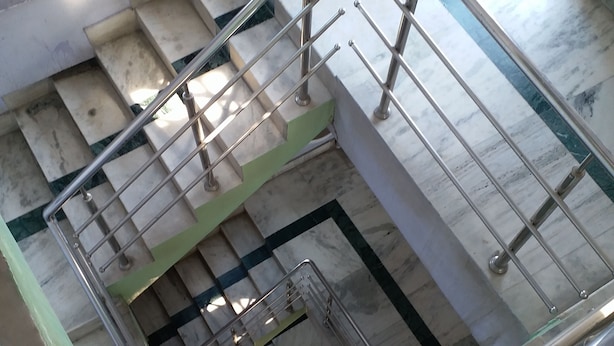 A staircase with a glass railing and metal handrails, leading to a lower level. - Kalita Boarding Home (Guwahati)