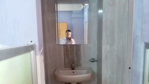 A bathroom with a sink, mirror, and tiled walls. - Kalita Boarding Home (Guwahati)