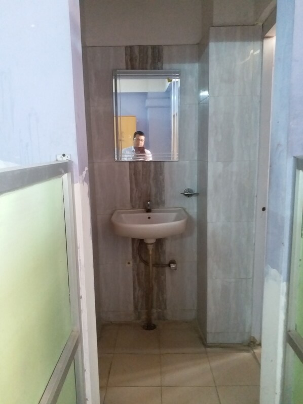 A bathroom with a sink, mirror, and tiled walls. - Kalita Boarding Home (Guwahati)