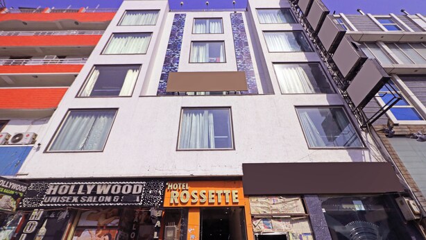 A hotel with multiple floors, a visible entrance, and signs for a Hollywood-themed bar and a Rosette hotel. - Hotel Rossette (New Delhi)