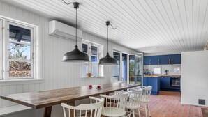 A modern kitchen with a long island, white chairs, and a brick floor. - "Gravers" - 150m from the sea by Interhome (Svendborg)