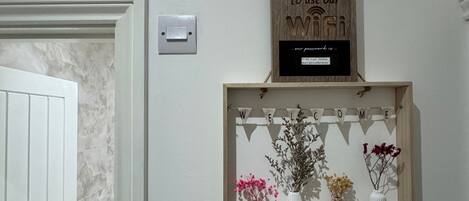 A wall-mounted shelf with a welcome sign and a thermostat.