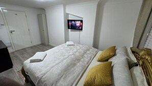 A hotel room with a bed, a TV mounted on the wall, and a door. - Cozy 2br-5guests-near Attractions-garden (London)