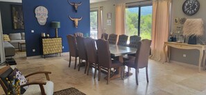 Un espace repas avec une table ronde et des chaises, un mur d’accent bleu agrémenté d’objets décoratifs, et une vue dégagée grâce à de grandes fenêtres.