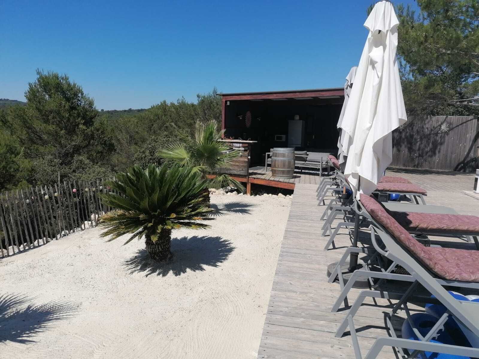 Un espace de détente aménagé au bord de la plage, avec des chaises longues et un coin salon abrité.