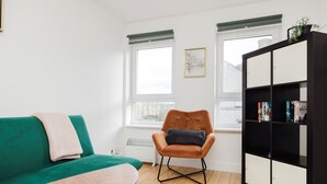 A modern living room with a green sofa, a brown armchair, a wooden coffee table, and a black and white bookshelf. - Welcoming 1BR flat near Park (Edinburgh)