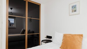 A bedroom with a bed, a nightstand, a wardrobe, and a window. - Welcoming 1BR flat near Park (Edinburgh)