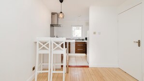 A kitchen with white cabinetry, a wooden floor, and a hanging pendant light. - Welcoming 1BR flat near Park (Edinburgh)