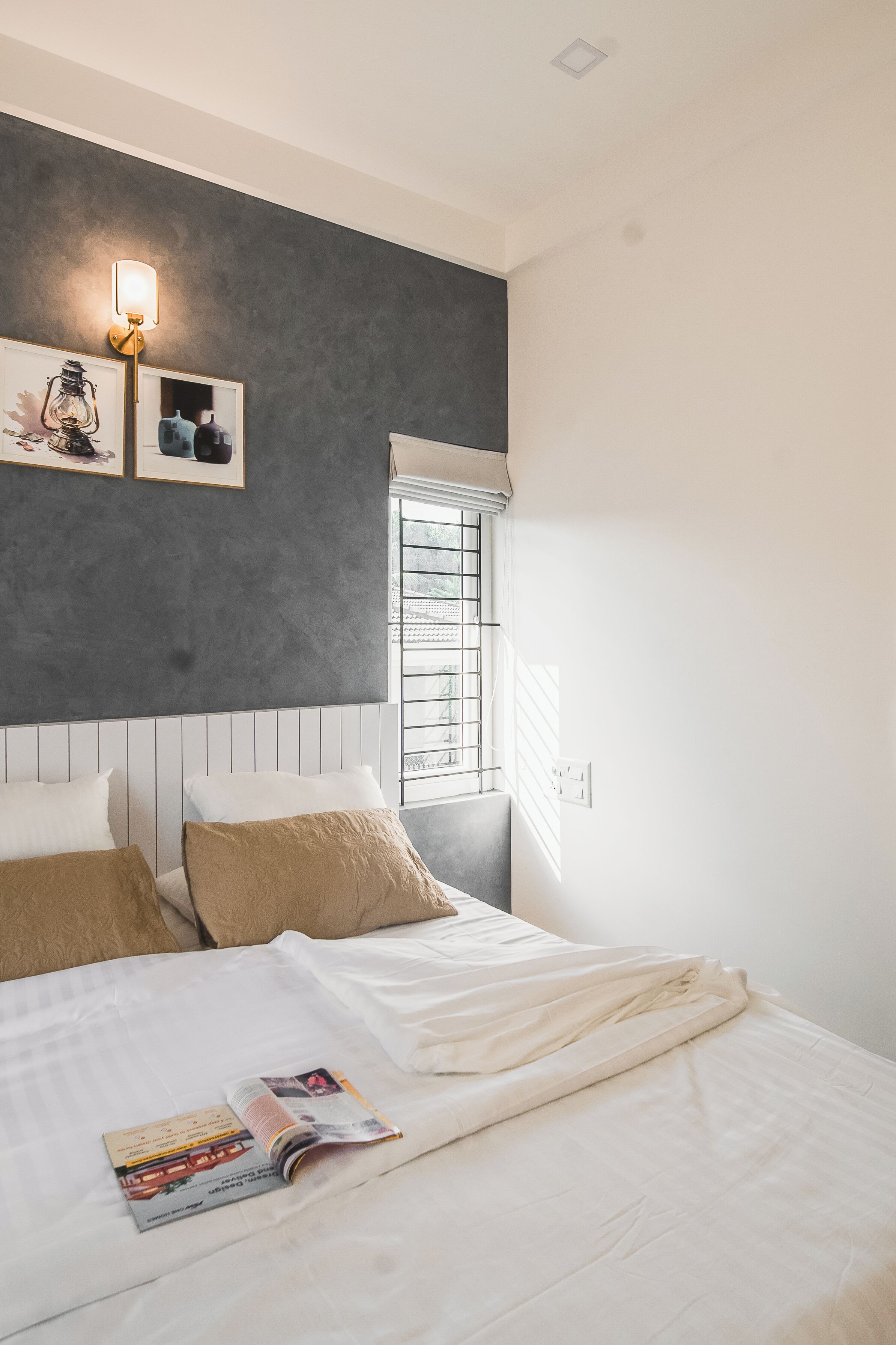 Un dormitorio con cama, ventana con persianas, lámpara de pared e imágenes enmarcadas.
