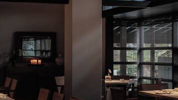 Un restaurante con poca luz, muebles de madera y ventanas amplias.