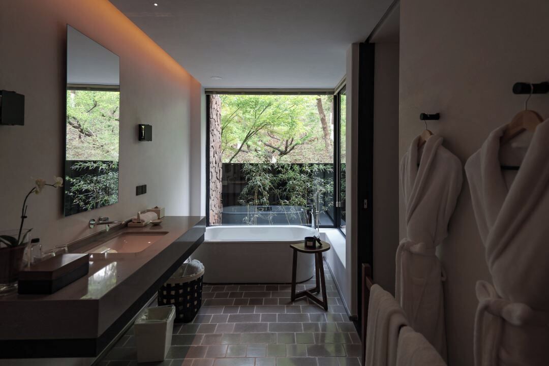 Un baño moderno con un ventanal grande, una bañera y un tocador con espejo.