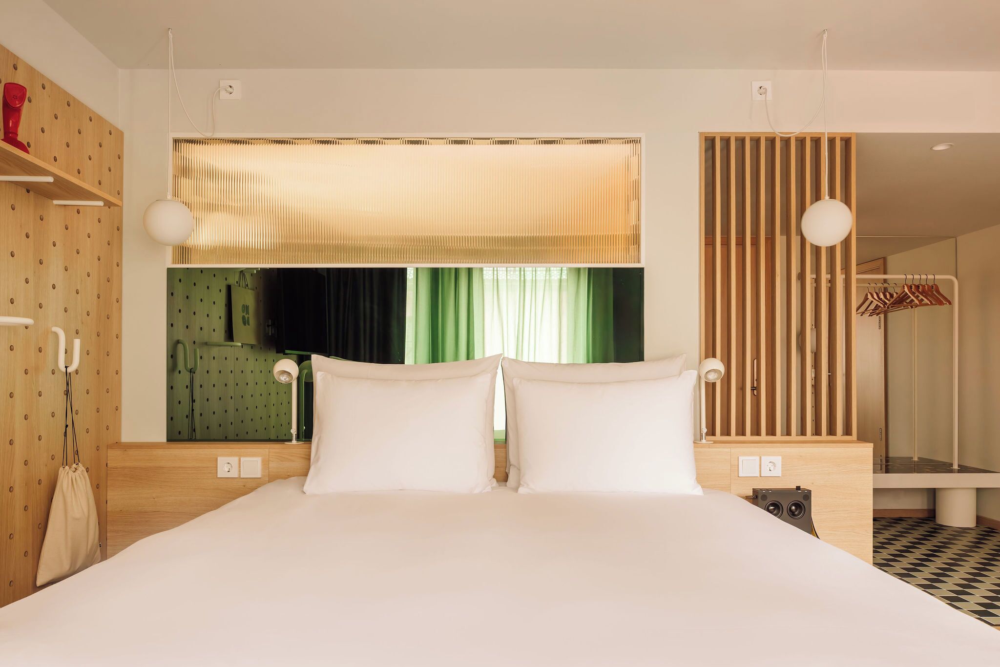 Una habitación de hotel moderna con una cama grande, un armario de madera, un espejo y una zona de ducha.
