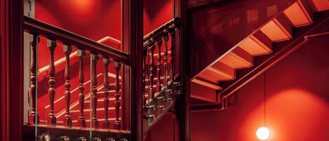 A multi-level staircase with wooden railings and glass panels, illuminated by warm lighting.