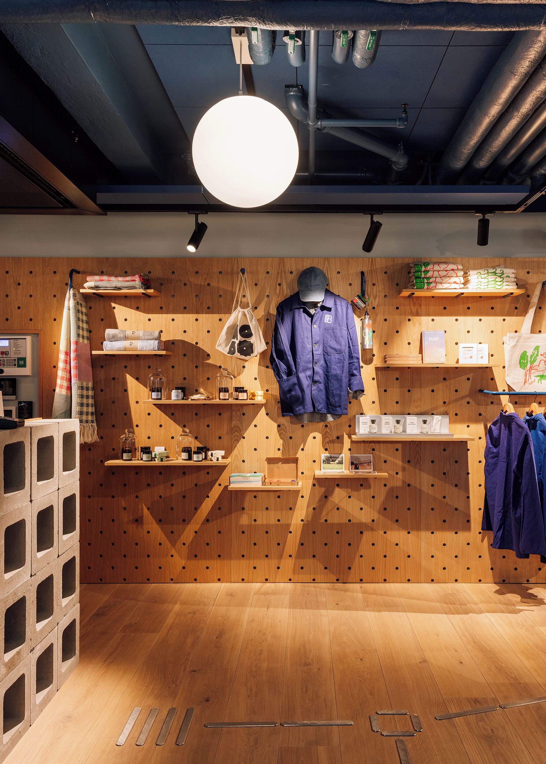 A retail space with wooden shelves displaying various products, a hanging garment, and a display of toiletries.