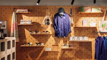 A retail space with wooden shelves displaying various products, a hanging garment, and a display of toiletries.