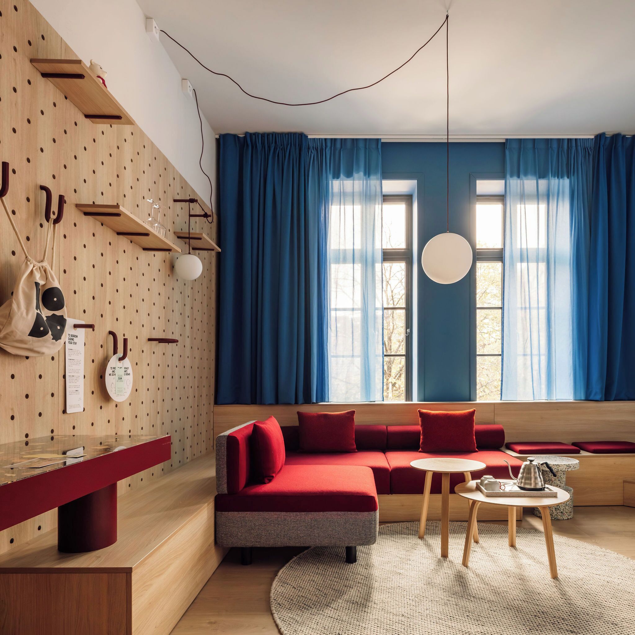 A modern living room with a red sofa, wooden shelves, and a round coffee table.