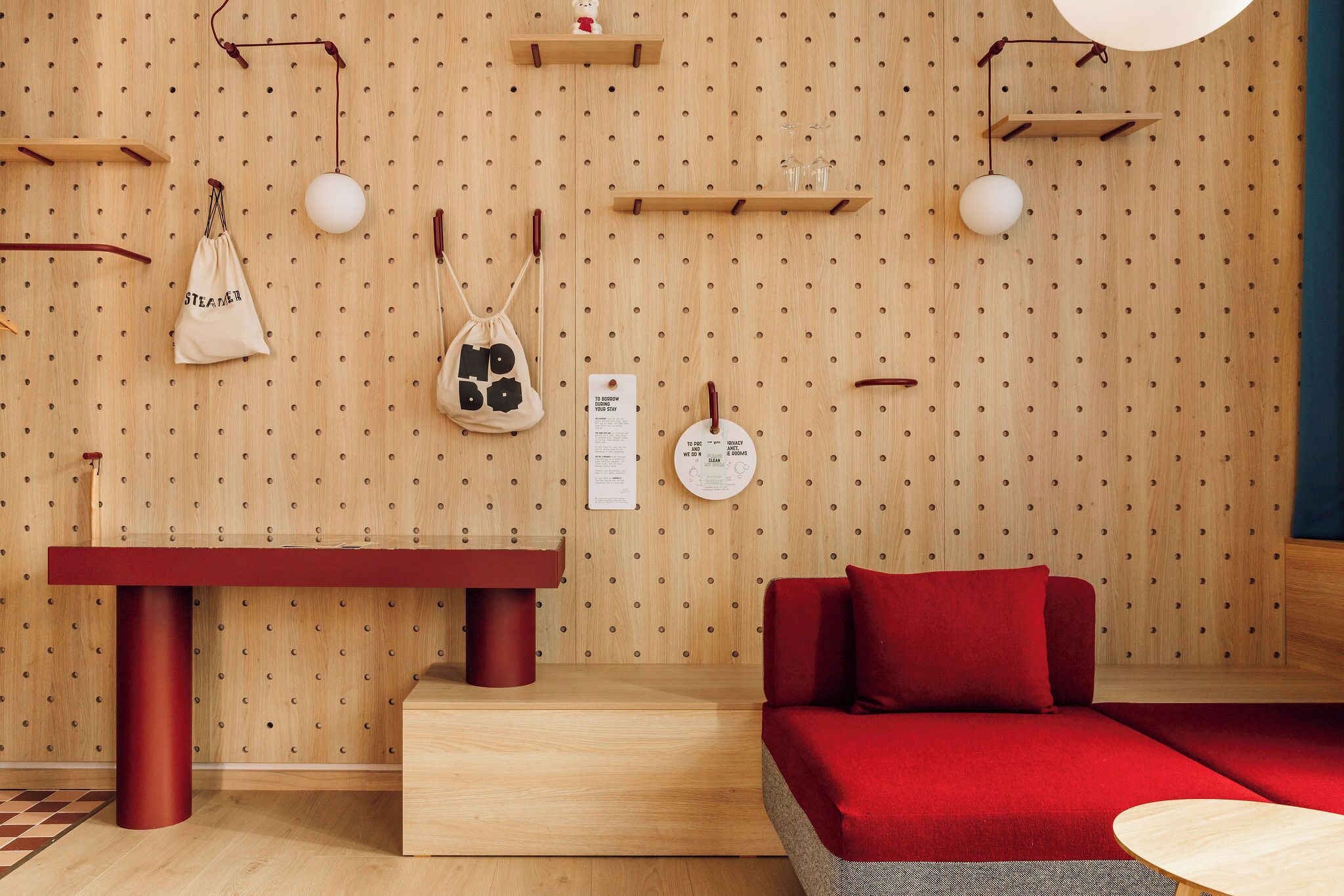 A modern room with a wooden wall, a red sofa, a red table, and a wooden bench.