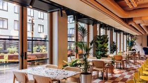 A restaurant with indoor seating, large windows, and potted plants. - Hobo Oslo (Oslo)