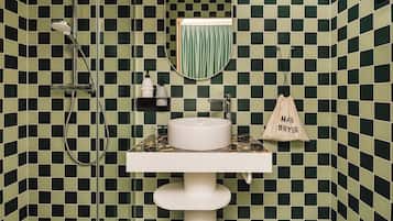 Een badkamer met een zwart-groen geruit tegelpatroon, een witte wastafel en een handdoek aan de muur.