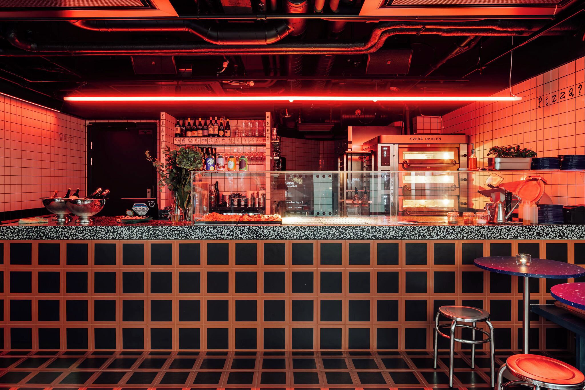 Eine Bar mit einer Theke, Hockstühlen und einem Kühlschrank.