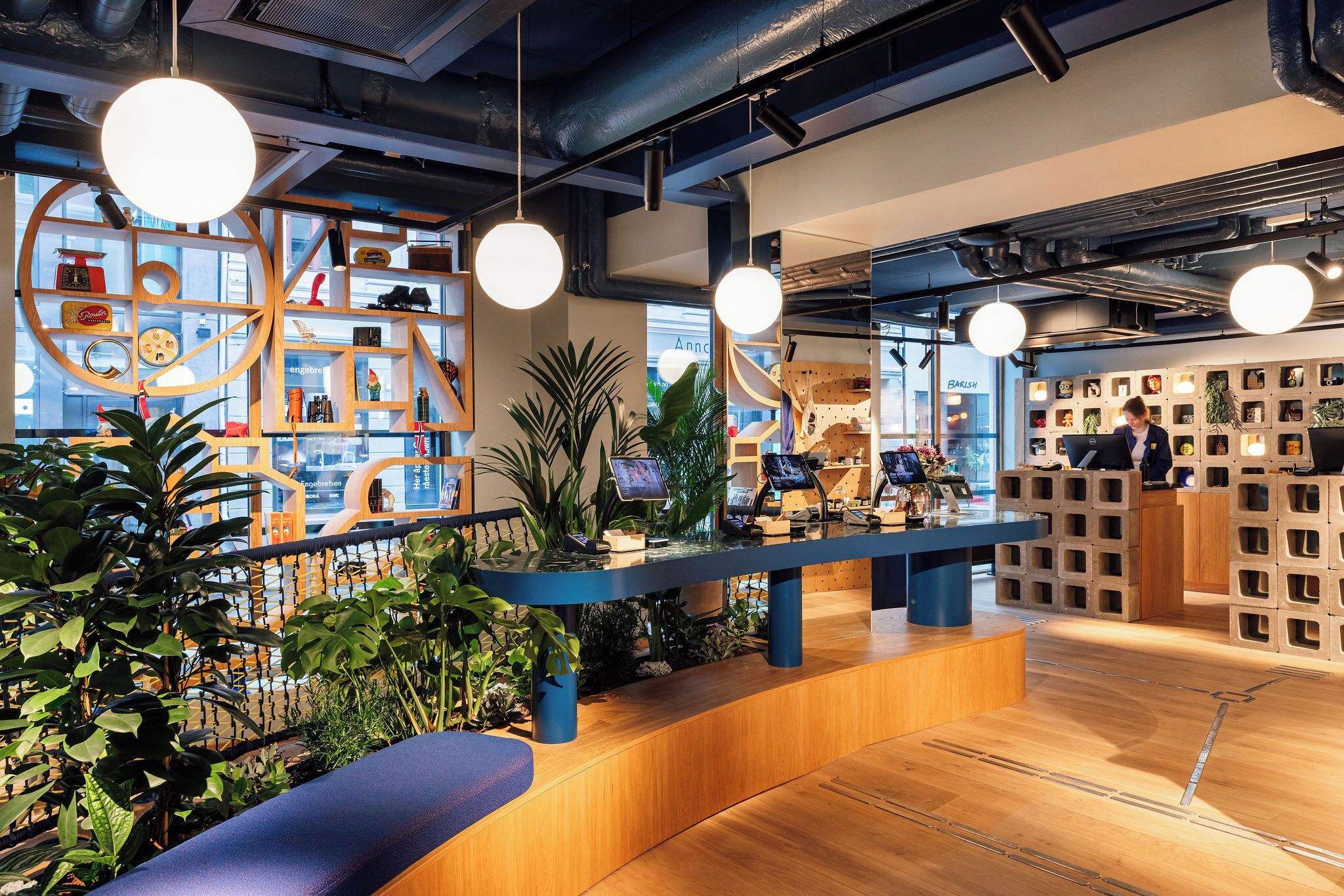 A modern reception area with a wooden reception desk, potted plants, and a seating area.