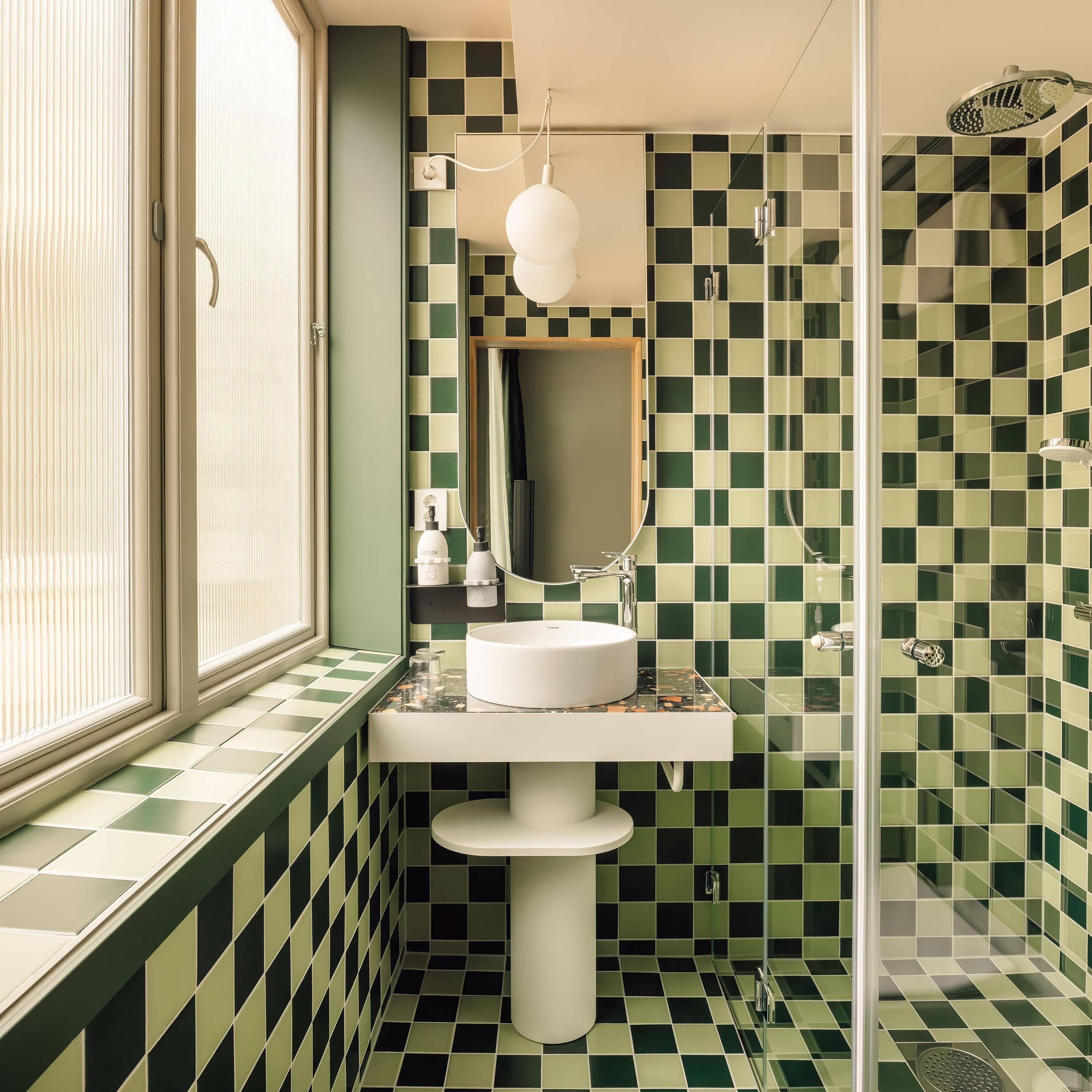 Ein Badezimmer mit Schachbrettfliesen, einem weißen Waschbecken, einem Spiegel und einer Dusche.