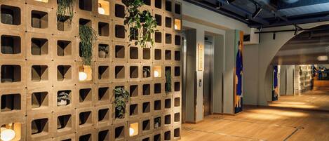 Un interior moderno con una pared de madera que tiene cuadrados recortados, algunos con plantas, y un piso de madera.
