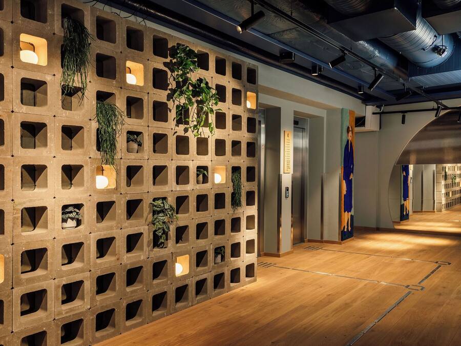 Ein modernes Interieur mit einer Holzwand, die quadratische Aussparungen aufweist, in einigen davon befinden sich Pflanzen, und einem Holzboden.